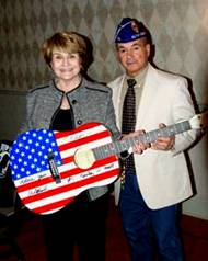 Louise Slaughter andGene Simes display Willie Nelson and Charlie Daniels signature guitar. 